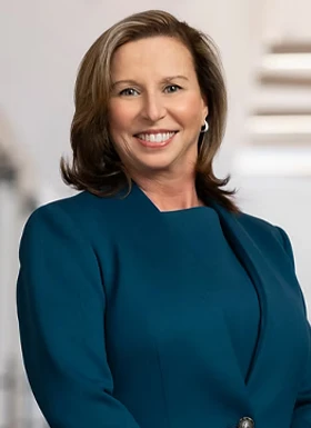 Professional woman in teal business attire smiling confidently in corporate setting